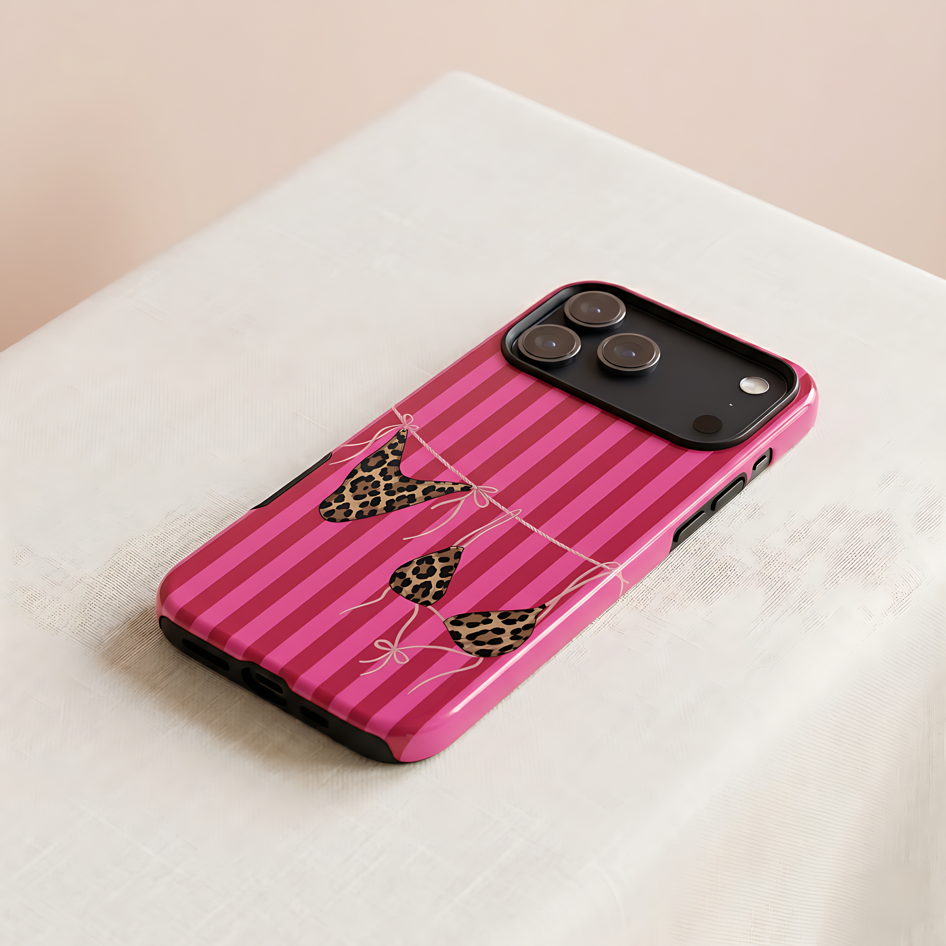 Pink striped phone case with leopard print accents on a light fabric background