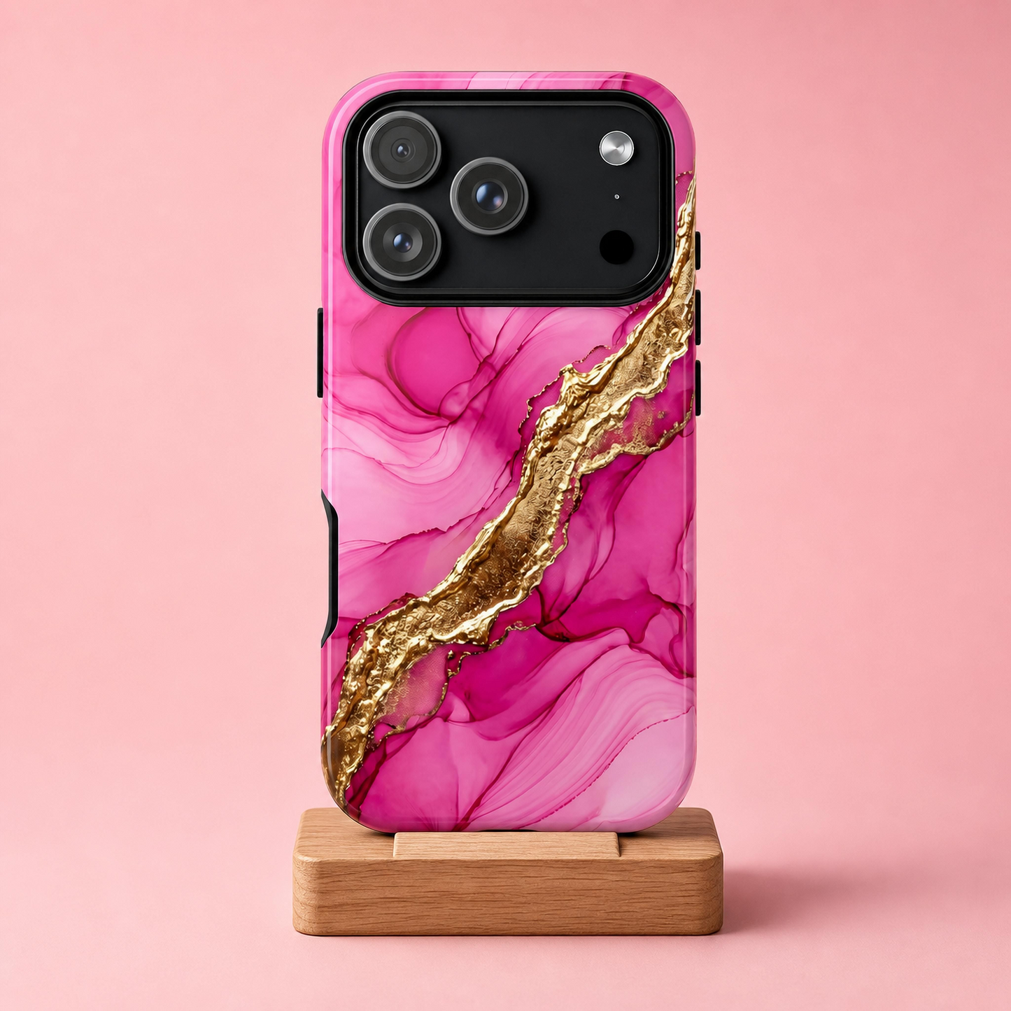 A pink marble-patterned phone case with a metallic gold diagonal veining design, shown on a wooden display stand against a solid pink background.