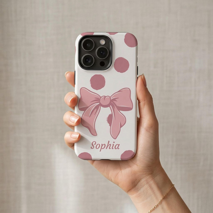 Phone case with pink bow and 'Sophia' text held by a hand against a neutral background